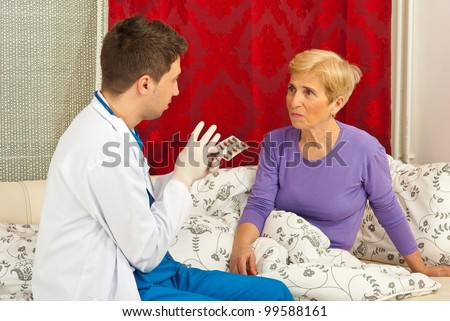 Doctor man explain to senior sick woman how to take the medicines and sitting on couch in home