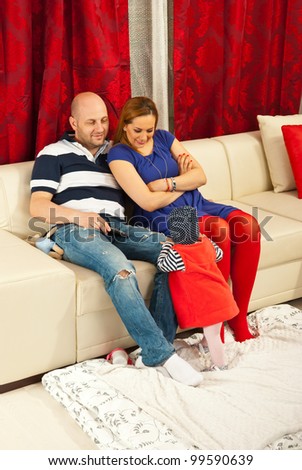 Cheerful mother and father talking with their baby in living room