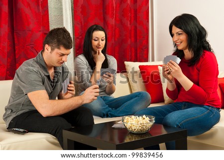 Friends playing cards and sitting together on couch