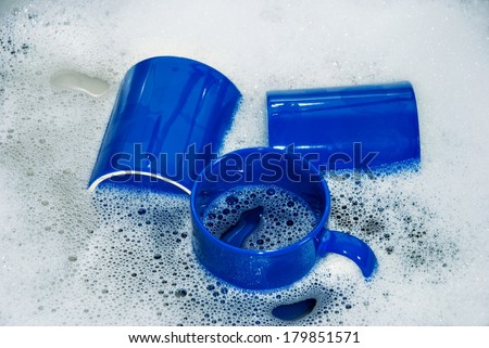 Three blue Coffee Cups in a Kitchen Sink with Dish Water, close up / Washing Dishes