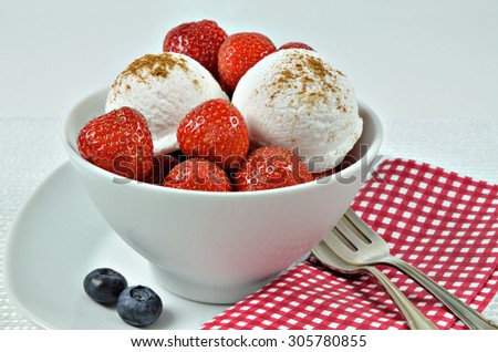 close up of a white bowl with vanilla ice cream, strawberries and blueberries, and a white and red checkered napkin,  macro, detail, horizontal / Vanilla Ice Cream with Strawberries and Blueberries