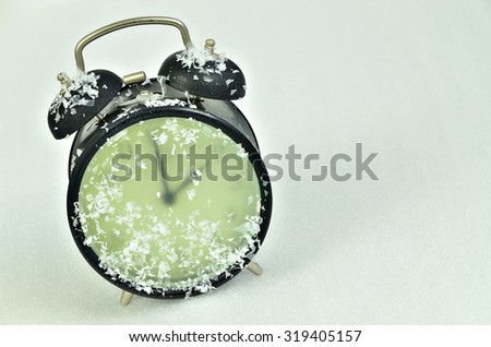 close up of  a snowy, frozen,  black retro alarm clock,  showing winter time, 2 am, horizontal, slanted  / Clock Change Winter Time