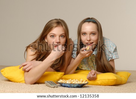 Two beautiful girls look cinema laying on a carpet