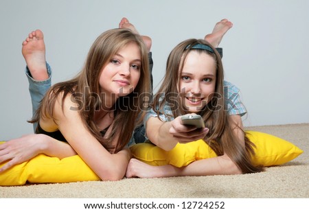 Two beautiful girls look cinema laying on a carpet