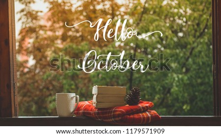 Hello October. Cozy autumn still life: cup of hot coffee and opened book on vintage windowsill with red blanket, pumpkin, pine cone, candles and rain outside. Autumn. Apartment. Rain