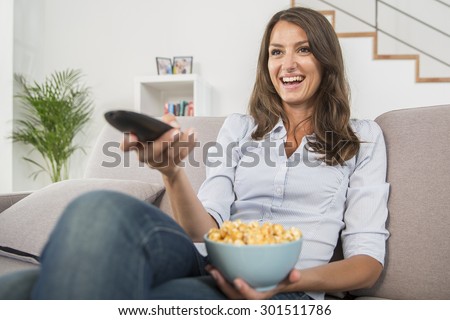 young woman with popcorn watching the tv