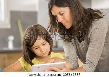 mother and daughter doing homework with a tablet