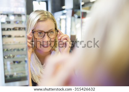 Woman in optical center trying eyeglasses on