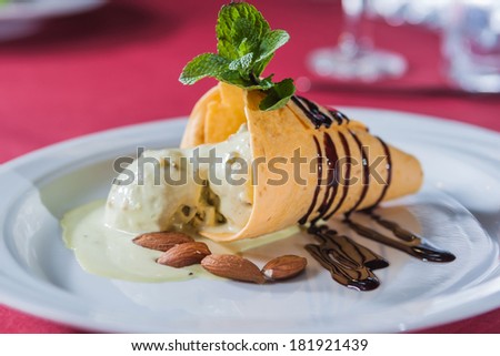 piece of ice cream with chocolate syrup, almonds and strawberry leaf