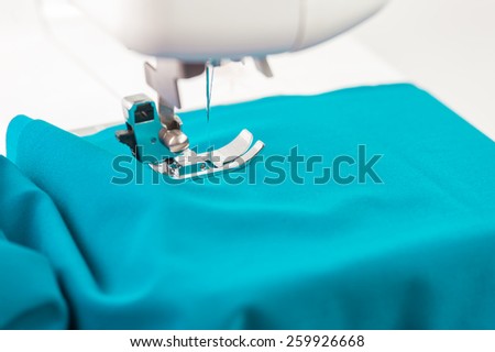Sewing machine paves the line on the turquoise fabric