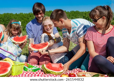 outdoor group portrait of happy company having picnic on green g