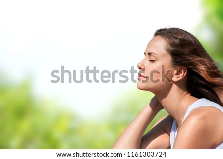 Calm beautiful smiling young woman with ponytail enjoying fresh air outdoor.