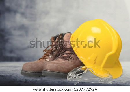 Yellow working hard hat, goggles and work boots on  background