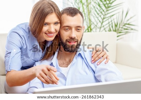 Laptop. Cheerful couple searching something on laptop at home