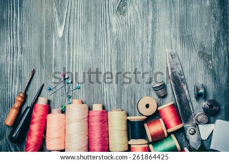 Craft. Vintage Background with sewing tools and colored tape/Sewing kit. Scissors, bobbins with thread and needles on the old wooden background
