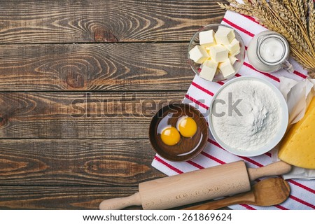 Cake. Baking cake in rural kitchen - dough recipe ingredients (eggs, flour, milk, butter, sugar) and rolling pin on vintage wood table from above. Rustic background with free text space.