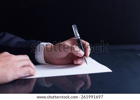 Lawyer. Businessman writing a letter, notes or correspondence or signing a document or agreement, close up view of his hand and the paper