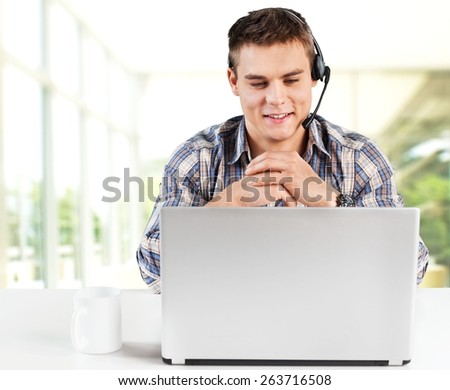 30s. Happy consultant with headset looking at laptop