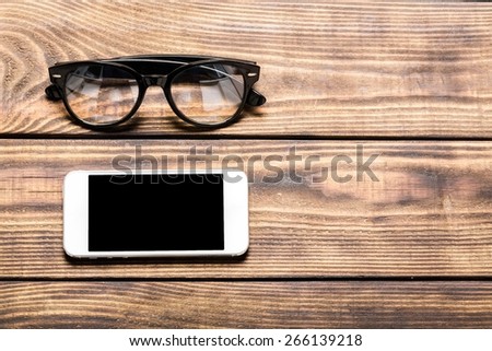 Desk. Old vintage books, smartphone and glasses on a wooden table