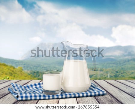 Milk. A glass of milk and a milk jug on plaid tablecloth.