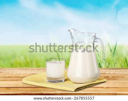 Milk. A glass of milk and a milk jug on plaid tablecloth.