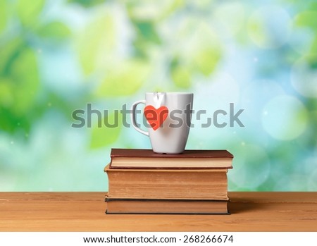 Backdrop. Coffee mug with heart shape on vintage books