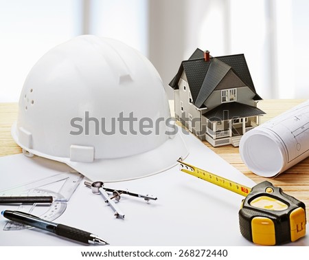 Concept. Safety helmet blue print plan and construction equipment on architect ,engineer working table with building construction  crane background use for construction industry business and civil