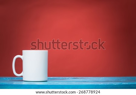 Tea. Red mug on wooden tabletop against grunge green wall