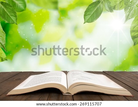 Book. Open book on wood planks over sky with leaves background