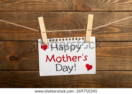 Day. Happy mothers Day message written on a aged paper handling on rope with hearts