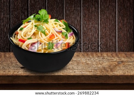 Spaghetti. Pasta in a white bowl with tomato sauce and fresh basil set against a white napkin on a white table.