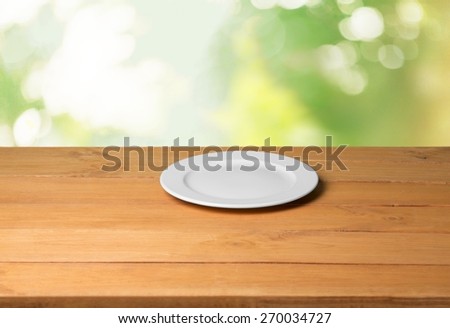 Plate. Empty plate on wooden table over nature background