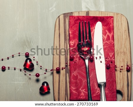 Dinner. Valentines day table setting with plate, knife, fork, red ribbon and hearts/ Holidays background/ Valentines day background