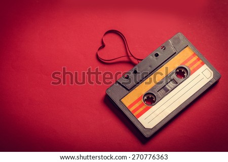 Music. Valentines day card. Vintage audio cassette with loose tape shaping a heart on red background