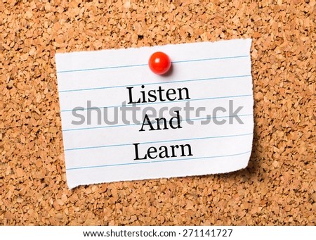 Studying. The phrase Listen and Learn  typed onto a scrap of lined paper and pinned to a cork notice board. This is the key to success in education and learning new skills for the workplace.