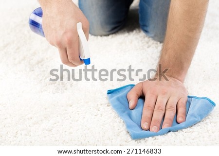 Adult. Cleaning and home concept - close up of male cleaning stain on carpet with cloth
