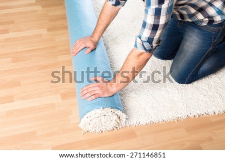 Carpet. Repair, building and home concept - close up of male hands unrolling carpet