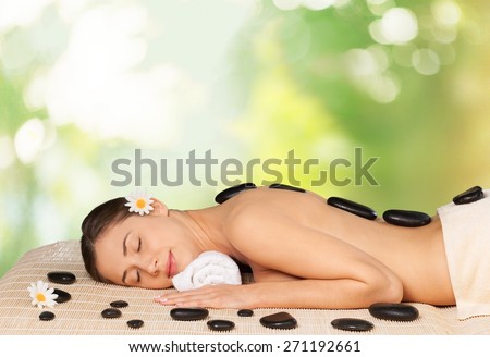 Spa Treatment. Spa salon: woman relaxing on mat with flowers and stones.
