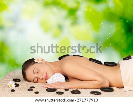 Spa Treatment. Spa salon: woman relaxing on mat with flowers and stones.