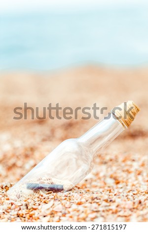 Travel. Bottle with message and shells on sand. Vacation concept