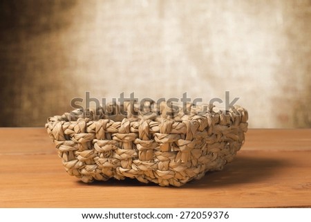 Advertise. Empty basket on wooden deck table over grunge background