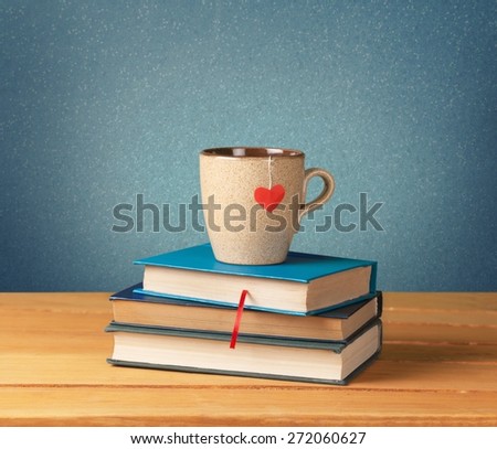 Tea. Old vintage books and cup with heart shape on wooden table