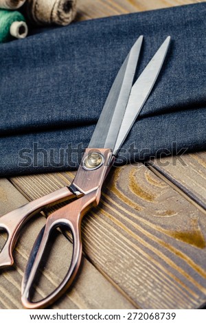 Tailored. Measuring and cutting textile or fine cloth. Work table of a tailor. Gold scissors and black fabric.