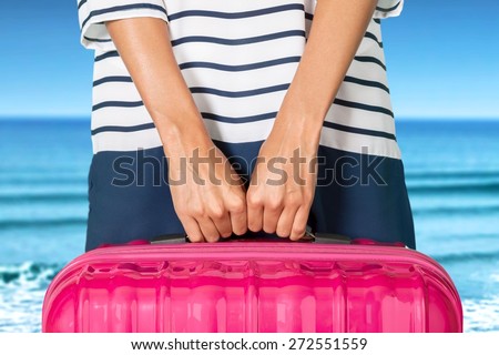 Woman. Woman in blue dress holds orange suitcase in hands on the beach background.