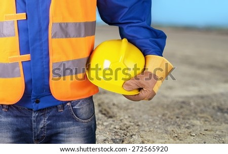 Arm. Builder with yellow helmet and working gloves on building site