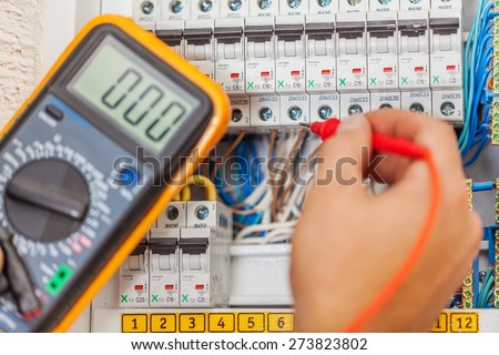 Electrician. Hand of an electrician with multimeter probe at an electrical switchgear cabinet