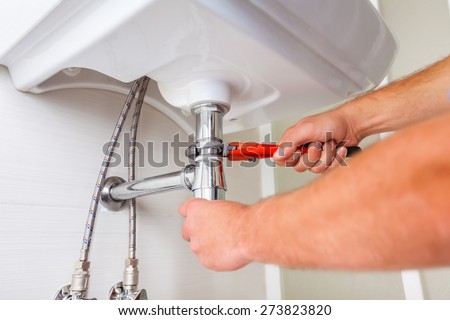 Wrench. Hands of professional Plumber with a wrench. Clogged sink.