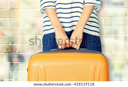 Woman holds orange suitcase.