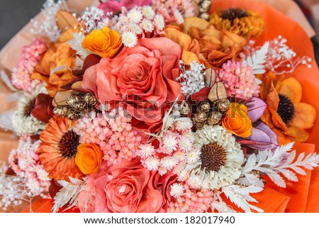 Detail of a colorful bouquet of dried flowers and artificial flowers in orange tone.