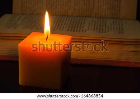 Candle and open book in the dark